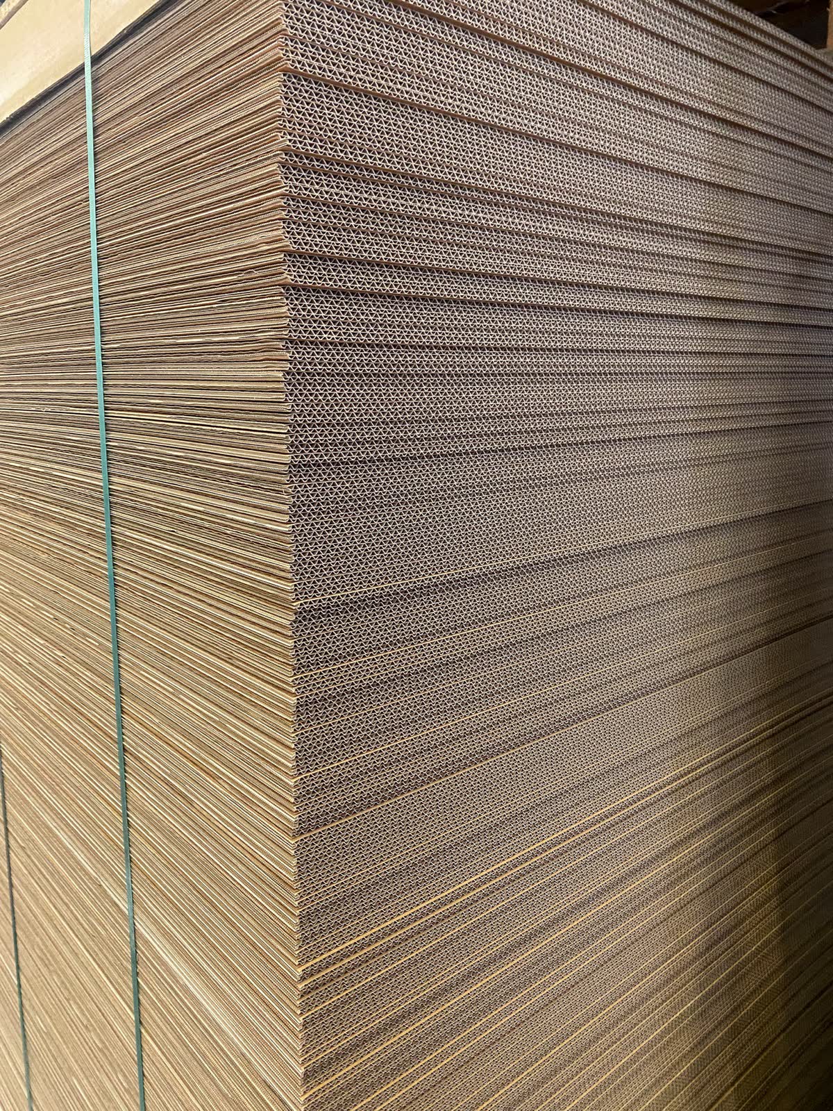 Close-up of a tall stack of corrugated cardboard sheets.